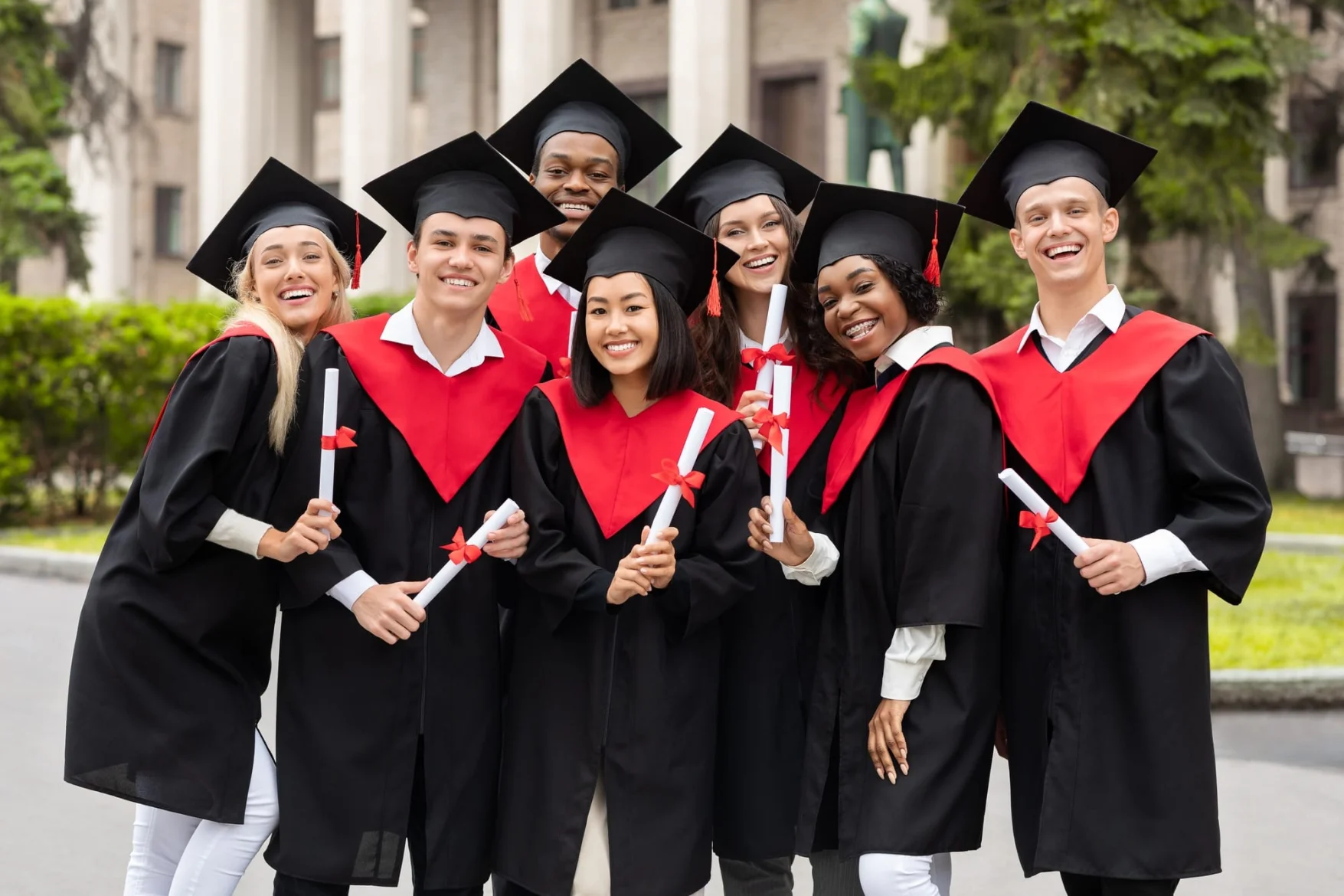 Cheerful multiracial students celebrating graduation, smiling at camera